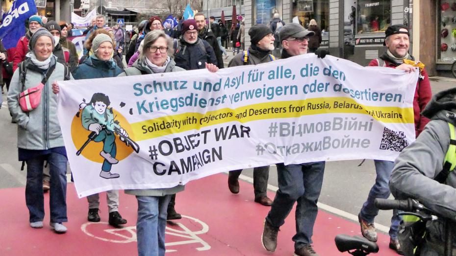 Bei einer Demonstration wird ein Transparent hochgehalten: Schutz und Asyl für alle, die den Kriegsdienst verweigern oder desertieren.