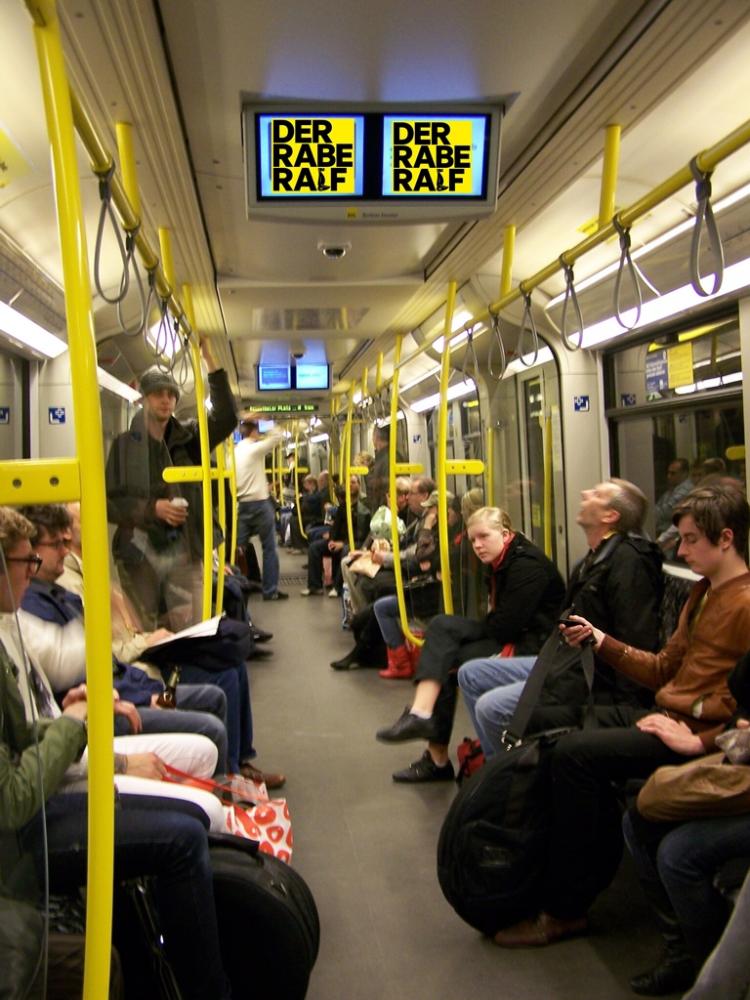 In einer gut gefüllten U-Bahn der Berliner Linie U8 ist auf den Monitoren des sogenannten Berliner Fensters statt Werbung und Nachrichten das Rabe-Ralf-Logo zu sehen.