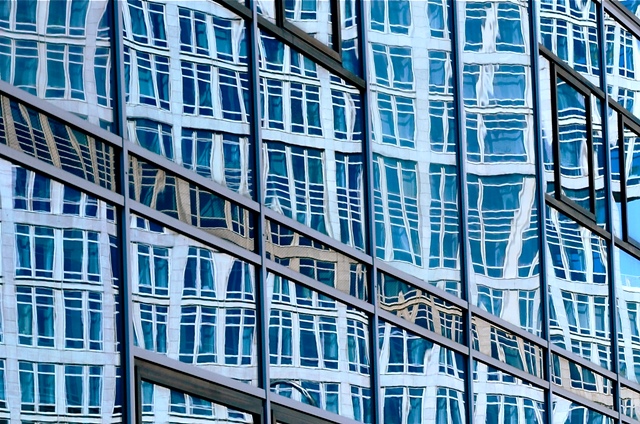 Ein Hochhaus spiegelt sich in den verspiegelten Fassaden eines anderen Hochhauses.