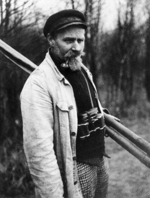 Ein schwarz-weiß Bild von einen Mann names Paul Robien. Er hat einen Kapitänshut auf, eine Pfeie im Mund und er trägt ein Fernrohr um den Hals.